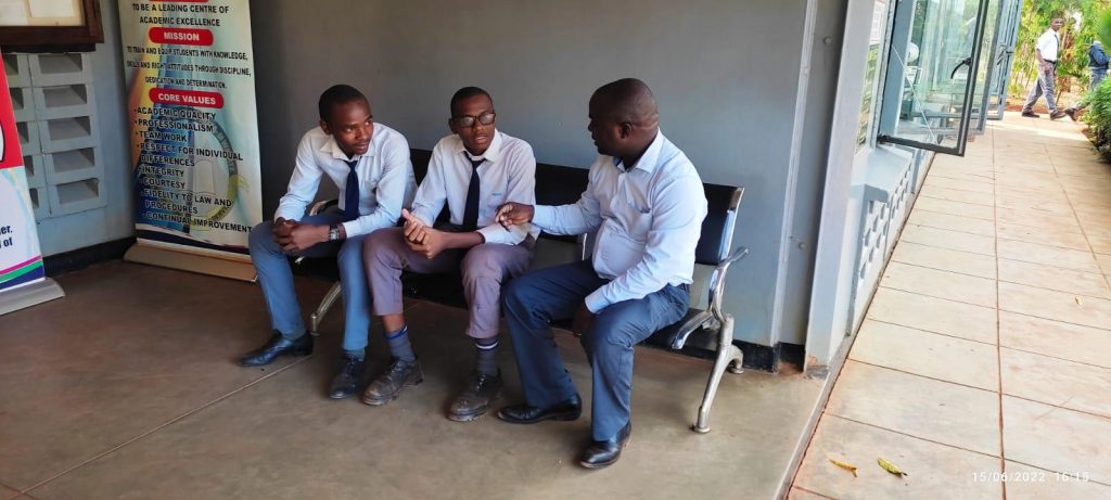 Harrison Mwakuchu (without specs) during a follow up meeting with Sebastian Mjomba a teacher and TATUA member